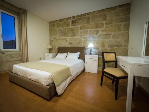 a bedroom with a bed and a desk and a chair at Casa Das Morgadas in Nelas