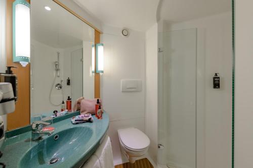 a bathroom with a sink and a toilet and a mirror at ibis Heilbronn City in Heilbronn
