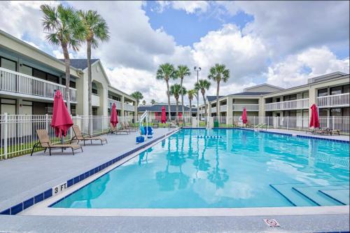 a swimming pool at a resort with chairs and umbrellas at Pool - WiFi - Gym - Parking - Best Location ! in Kissimmee