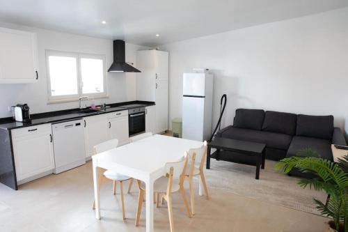 uma cozinha e uma sala de estar com uma mesa branca e cadeiras em Barra Beach House 2 em Gafanha da Nazaré