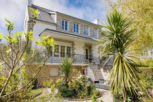 a white house with blue windows and palm trees at ARVEIL in Plomeur
