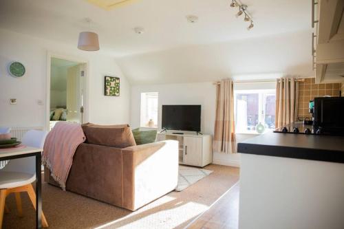 a living room with a couch and a television at Laburnum Maisonettes by Oracle in Stratford-upon-Avon