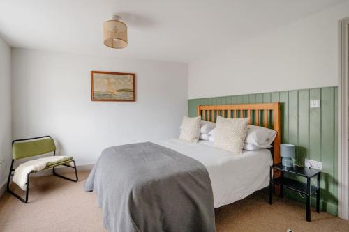 a bedroom with a large bed and a chair at Cosy cottage near the coast in Tywardreath