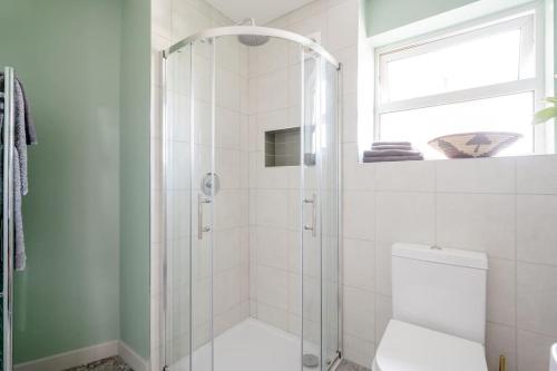 a bathroom with a shower with a toilet and a window at Cosy cottage near the coast in Tywardreath