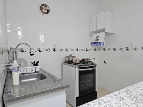 a white kitchen with a sink and a stove at Apto novo, mobiliado e acochegante in Boa Vista