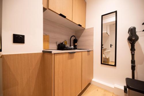 - une cuisine avec des placards en bois et un miroir dans l'établissement Cosy flat / Tour Eiffel Area, à Paris