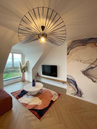 un salon avec un grand lustre et une chambre avec une table dans l'établissement La Félicita Calais Plage, à Calais