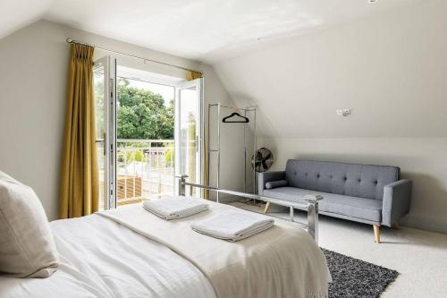 um quarto com uma cama, um sofá e uma janela em Luxury, eco-friendly 3 bed haven with plunge pool - Riverway Retreat Lux em Christchurch