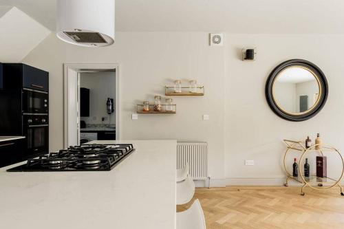 a white kitchen with a stove and a mirror at Luxury, eco-friendly 3 bed haven with plunge pool - Riverway Retreat Lux in Christchurch