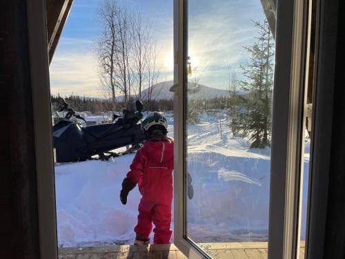 a child standing in front of a door at Glamping wooden house in Borgafjäll