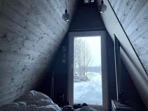 ein Schlafzimmer mit einem Fenster in einem Zimmer mit Schnee in der Unterkunft Glamping wooden house in Borgafjäll