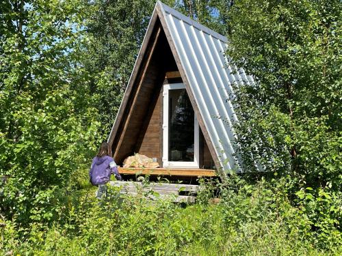 a woman sitting in front of a tiny house at Glamping wooden house in Borgafjäll