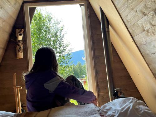 a woman looking out the window of a tent at Glamping wooden house in Borgafjäll