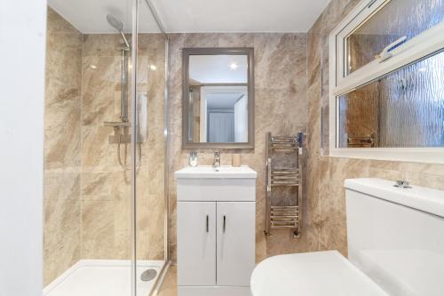 a bathroom with a shower and a sink and a mirror at The Wood Green Collection in London