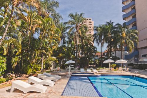 Gran Hotel Morada do Sol في أراراكارا: مسبح مع كراسي الصالة والنخيل