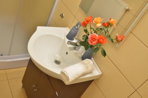 a bathroom sink with a vase of flowers on it at Vila Bel Ami in Şelimbăr