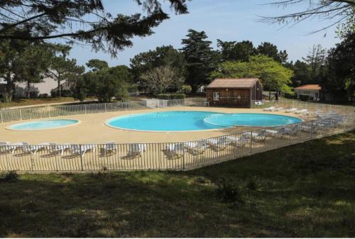 une grande piscine avec des chaises et un gazebo dans l'établissement Maisonnette Mimosa H3 avec piscine intérieure chauffée à 400 m de la plage et ménage de fin de séjour compris, à Les Sables Vignier