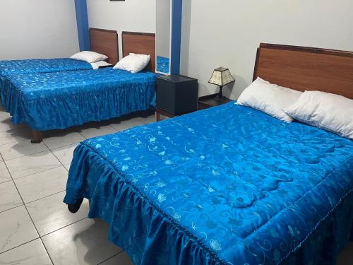 two beds with blue sheets in a room at Posada de Percybal Mirador in Puno