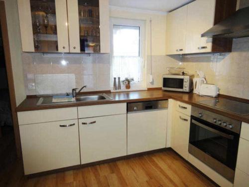 a kitchen with white cabinets and a sink and a microwave at Ferienhaus Grüner Winkel - Nähe Strandstraße in Müritz
