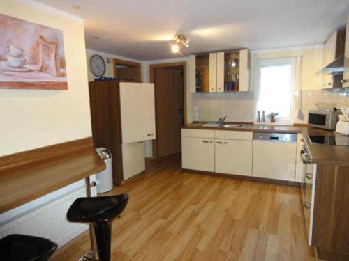 a kitchen with white cabinets and a wooden floor at Ferienhaus Grüner Winkel - Nähe Strandstraße in Müritz