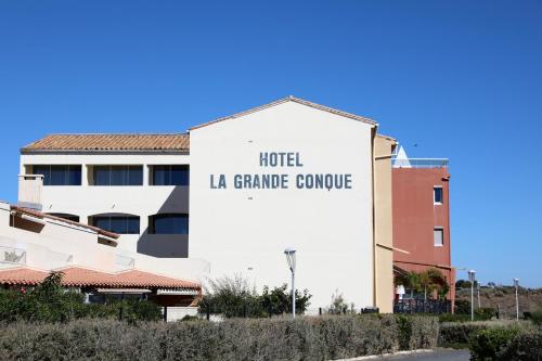 a building with a sign for a hotel la grande concourse at Hôtel La Grande Conque in Cap d'Agde