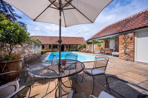 a patio with a table and an umbrella and a pool at Ivy Farm 8 in Grimston