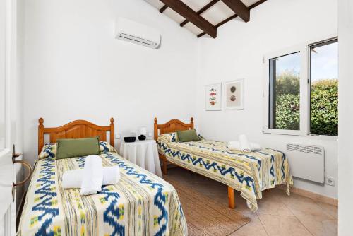 due letti in una stanza con pareti bianche e una finestra di Villa Bini Yaya - Cap den Font a Sant Lluís