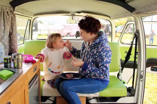 uma mulher e uma menina sentados numa carrinha em eDub Indie - The 100% Electric Classic Camper em Great Ouseburn