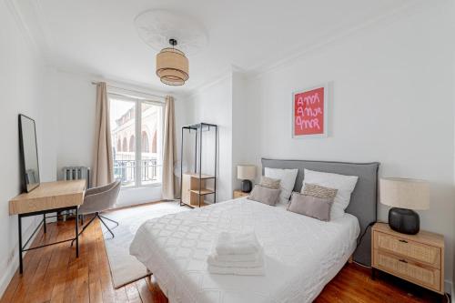 une chambre blanche avec un lit et un bureau dans l'établissement Parisian Elegance 2bedr in the 16th, à Paris
