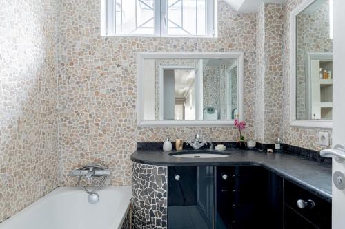 une salle de bain avec un lavabo et un miroir dans l'établissement Parisian Elegance 2bedr in the 16th, à Paris