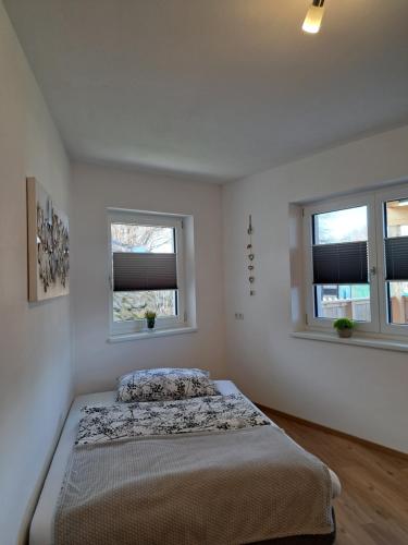 um quarto com uma cama e duas janelas em Ferienwohnung Abenthung em Grinzens