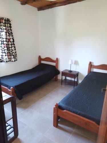 1 dormitorio con 2 camas y mesa con lámpara en El Caburé en Concepción del Uruguay