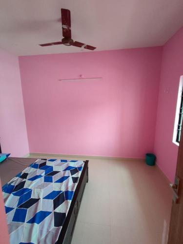 Habitación con cama y pared de color rosa en NIVAS HILL VIEW APARTMENTS en Tiruvannāmalai