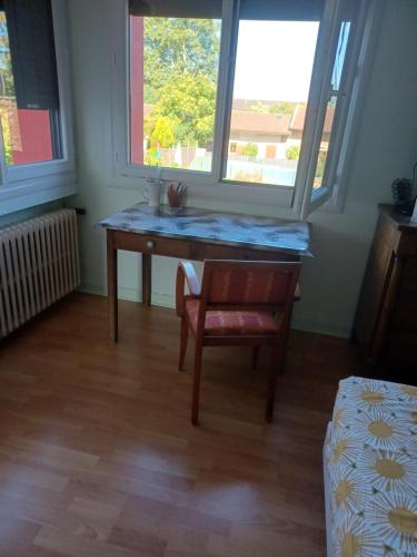 a desk in a room with a chair and a window at Chambre indépendante in Replonges