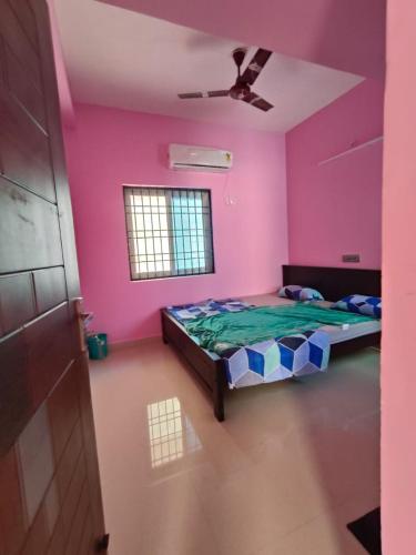 Habitación rosa con cama y ventilador de techo. en NIVAS HILL VIEW APARTMENTS en Tiruvannāmalai