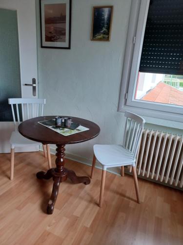 une table et deux chaises dans une pièce avec une fenêtre dans l'établissement Chambre calme et agréable, à Replonges