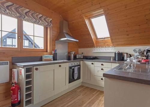 a large kitchen with white cabinets and a stove at Gwel an Mor in Portreath