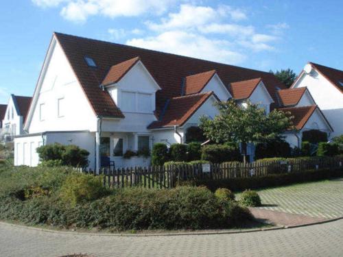 a large white house with a fence in front of it at Haus Heidelbeere 26 in Graal-Müritz
