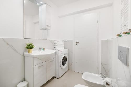 une salle de bain blanche avec une machine à laver et un lavabo dans l'établissement Blissful Haven Flats, à Oradea