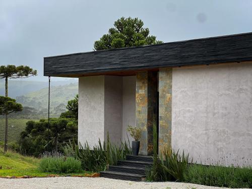ein kleines Haus mit schwarzem Dach und Treppe in der Unterkunft Jardim das Pedras in Bom Jardim da Serra
