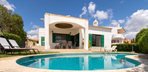 a villa with a swimming pool in front of a house at TAC - Vila Tina Vilamoura in Quarteira