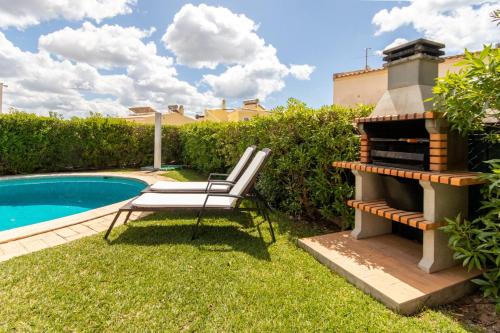 a chair sitting next to a barbecue next to a pool at TAC - Vila Tina Vilamoura in Quarteira