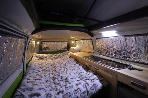 uma cama grande na parte de trás de uma caravana em eDub Indie - The 100% Electric Classic Camper em Great Ouseburn