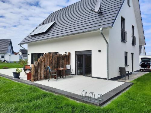 a white house with a patio with a table and chairs at Haus Luca - an den Müritzer Küstenwiesen in Müritz