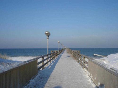 a boardwalk leading to the ocean with snow on it at Haus Malta - Strandstraße in Müritz