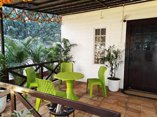 a patio with green chairs and a table and a door at Shobhayan inn, airport railway station pickup free in Ayodhya