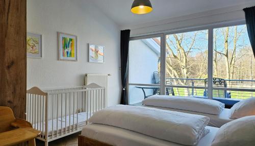 - 3 lits dans une chambre avec une grande fenêtre dans l'établissement Ferienwohnung Meerzeit, à Kühlungsborn