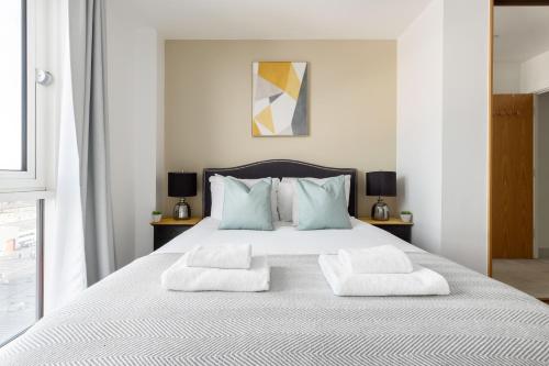 a bedroom with a white bed with two pillows at The Bow Flats in London