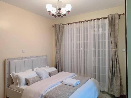 a bedroom with a large bed with a chandelier at Spire Plaza 2 bedroom apartment in Nairobi