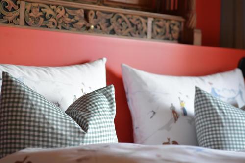a bed with green and white pillows and a red headboard at Casa Fausta Capaul in Brigels